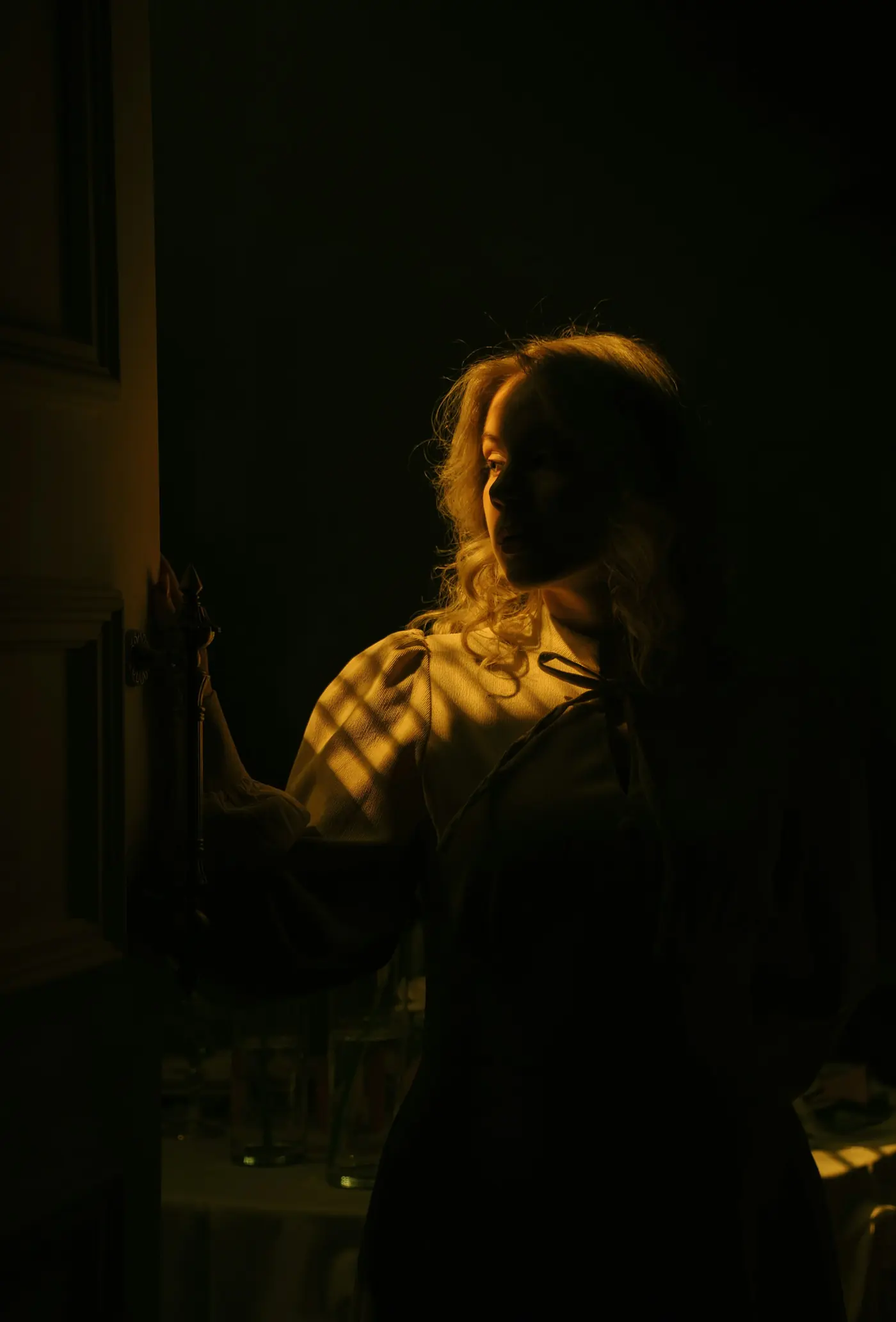 Une femme dans la pénombre, le visage éclairé par une lumière chaude
