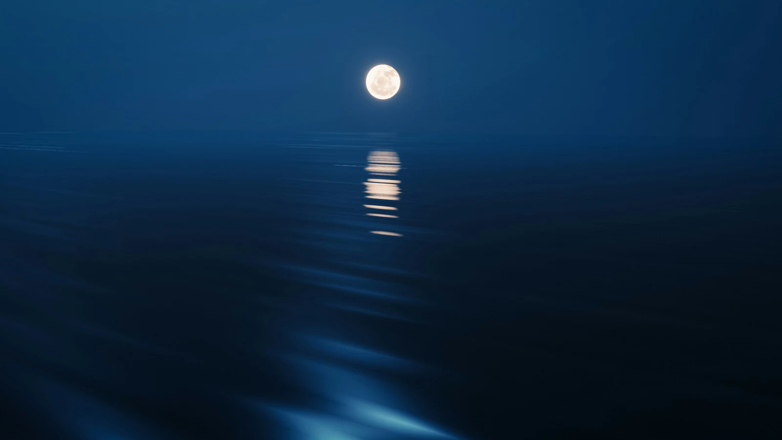 Pleine lune se levant sur l'océan, son reflet traçant un chemin de lumière sur l'eau