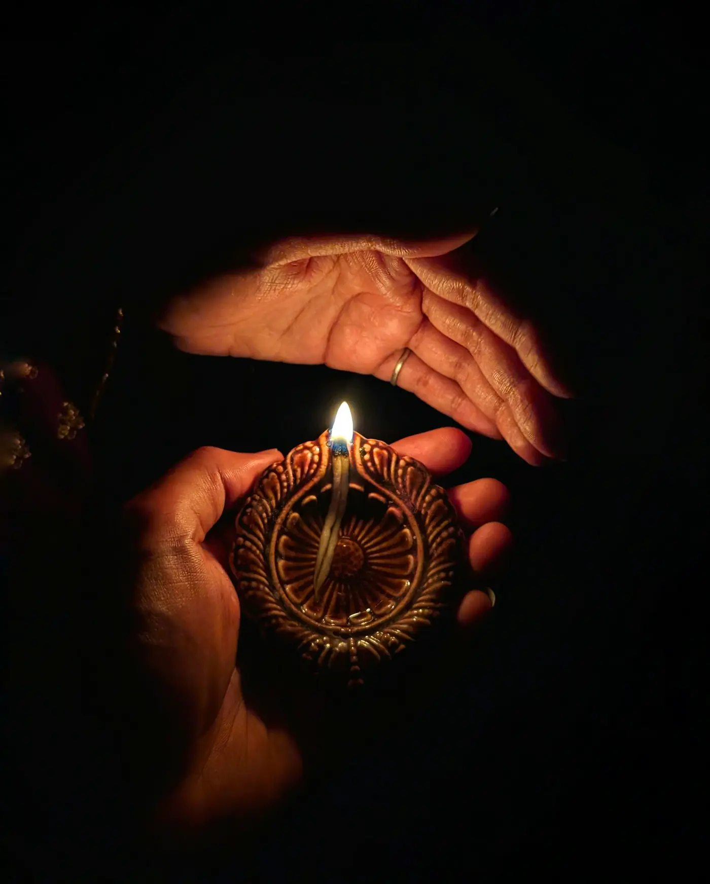 Des mains protègent une petite flamme